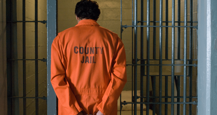 man walking into cell with county jail jumpsuit on