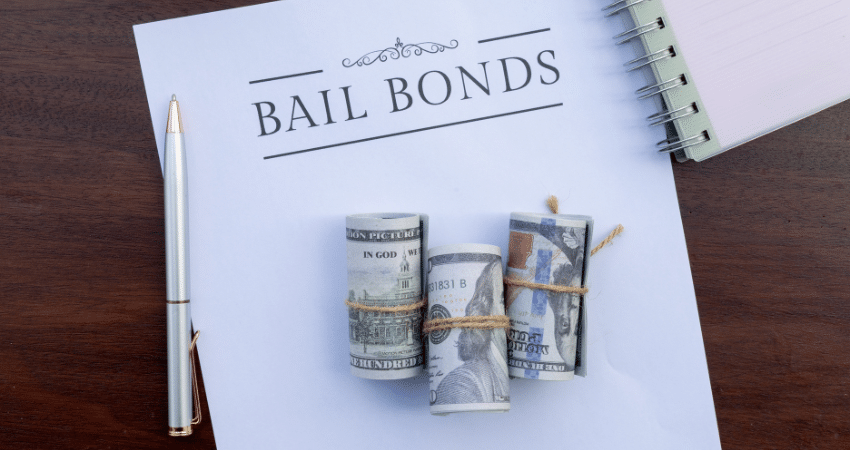 paper says bail bonds with rolls of rubber band cash on top
