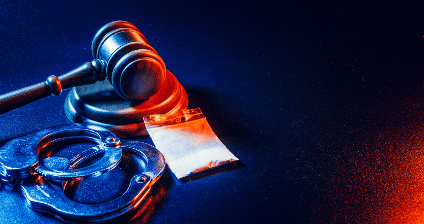 gavel handcuffs and bag of white powder on dark table